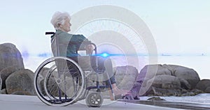 Animation of light moving over smiling senior caucasian woman in wheelchair on beach looking to sea