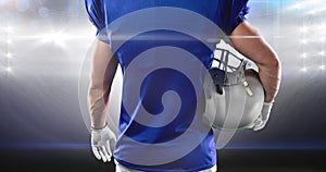 Animation of lights over midsection of american football player holding helmet at floodlit stadium