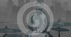 Animation of moving cityscape over caucasian man playing drums in black and white