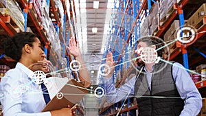 Animation of network of digital icons over team of diverse supervisors high fiving at warehouse