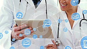 Animation of network of media icons over caucasian female and male doctor using tablet