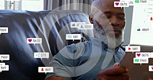 Animation of notification bars over senior african american man using digital tablet at home