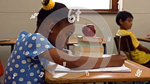 Animation of numbers over african american schoolgirl writing in notebook at school