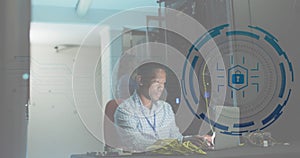 Animation of padlock in circle over african american male engineer using laptop at data centre