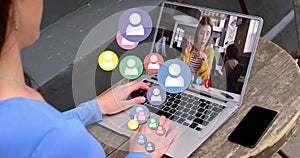 Animation of profile icons floating over rear view of woman having a video call on laptop at a cafe