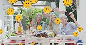 Animation of smiley faces over happy caucasian family taking selfie in garden
