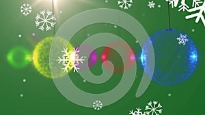 Animation of snow falling over christmas boubles on green background