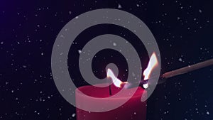 Animation of snowflakes falling over match lighting red candle on black background