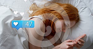 Animation of social media reactions over caucasian woman using smartphone in bed