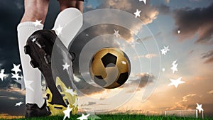 Animation of stars over feet of caucasian soccer player and gold ball at sunset