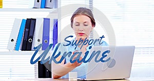 Animation of support ukraine over caucasian buisnesswoman using laptop