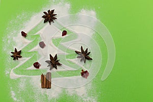 Anise and cinnamon spices christmas tree shape on green background