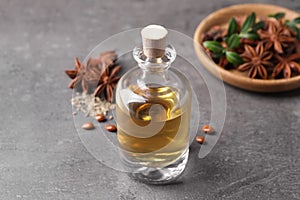 Anise essential oil and spices on grey table