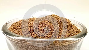 Anise seeds drops in a glass bowl on white background, a glass bowl full of anise seeds in the center,