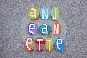 Anjeanette, feminine given name composed with multi colored stone letters over beach sand
