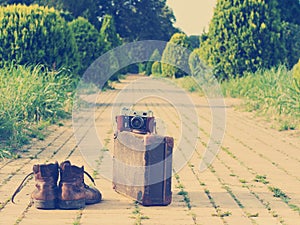 Ankle boots, cardboard suitcase, film camera, brick road. Post-processed.