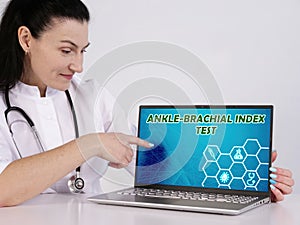 ANKLE-BRACHIAL INDEX TEST inscription on the screen. Close up physician hands holding pen photo