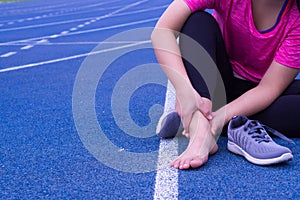 Ankle sprained. Young woman suffering from an ankle injury while jogging and running on running track. Healthcare and sport