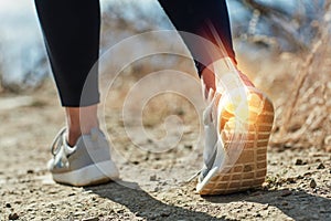 That ankles taking some strain. Shot of an unrecognizable woman running outdoors with a highlighted ankle injury.