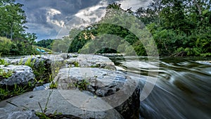 Ann arbor cascades park with moving water flowing along rocks under a blue sky photo