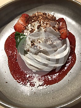 Anna Pavlova dessert with strawberry sauce and mint