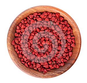 Annatto seeds in wooden bowl, isolated on a white background. Achiote seeds, bixa orellana. Natural dye for cooking and