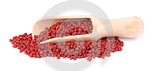 Annatto seeds, in the wooden spoon, isolated on white background. Achiote seeds, bixa orellana. Natural dye for cooking