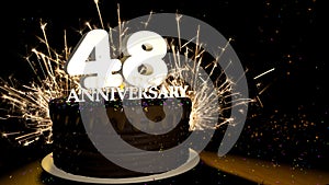 Anniversary 48 greeting card. Chocolate cake decorated with colored dragees with white numbers on a wooden table with fireworks in