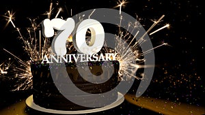 Anniversary 70 greeting card. Chocolate cake decorated with colored dragees with white numbers on a wooden table with fireworks in