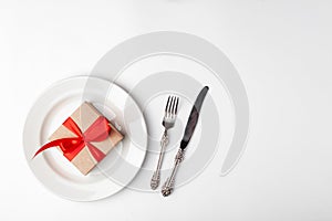 Anniversary, birthsday festive romantic table setting on white background. Kraft gift box with red ribbon in ceramic