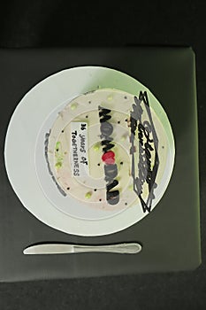 Anniversary cake with black and white frosting and green decoration.