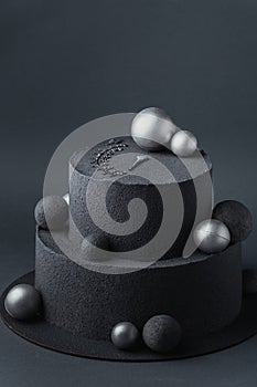 Anniversary luxury black bunk cake with chocolate velvet coating on dark grey background. Birthday cake with black velvet texture