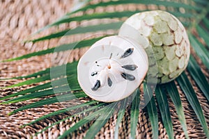 Annona muricata or soursop, graviola and guyabano with palm leaves on rattan background. Copy space. Creative design banner.
