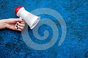 Announcement concept. Megaphone in hand on blue background top view copy space