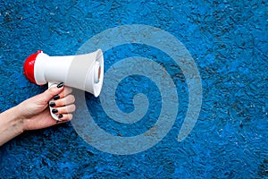 Announcement concept. Megaphone in hand on blue background top view copy space