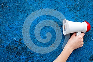Announcement concept. Megaphone in hand on blue background top view copy space