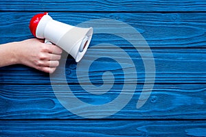 Announcement concept. Megaphone in hand on blue wooden background top view copy space