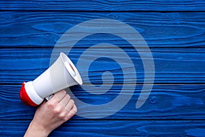 Announcement concept. Megaphone in hand on blue wooden background top view copy space