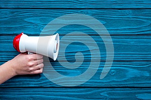 Announcement concept. Megaphone in hand on blue wooden background top view copy space