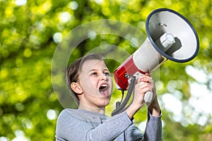 Announcing concept, boy shouting or screaming through the megaphone over forest background with copyspace