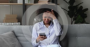 Annoyed African woman read sms on smartphone with bad news