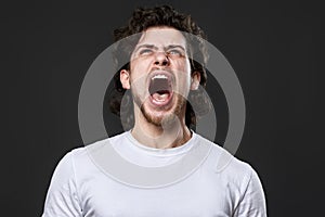 annoyed angry curly bearded man on dark gray studio background