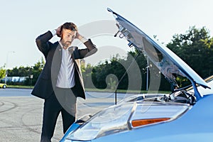 An annoyed and angry man, near a broken car, tries to call an insurance agent and a repair crew. for car repair