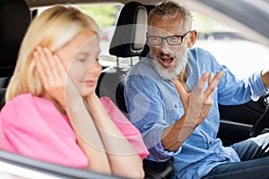 Annoyed angry senior man driver shouting at his stressed wife