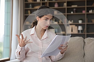 Annoyed angry young woman holding documents with bad frustrating news