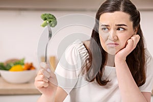 Annoyed bleak woman eating broccoli