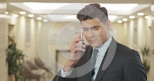 Annoyed businessman listening to yelling in smartphone. Portrait of irritated young Caucasian man talking on the phone