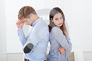 Annoyed couple standing back to back at home