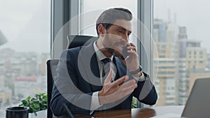 Annoyed director arguing phone call sitting at office desk closeup. Man shouting