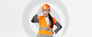 Annoyed and disappointed female asian chief engineer scolding construction workers making stupid mistake, tap helmet and